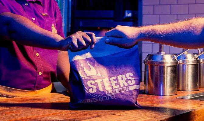 Cashier handing off a takeaway parcel to a customer